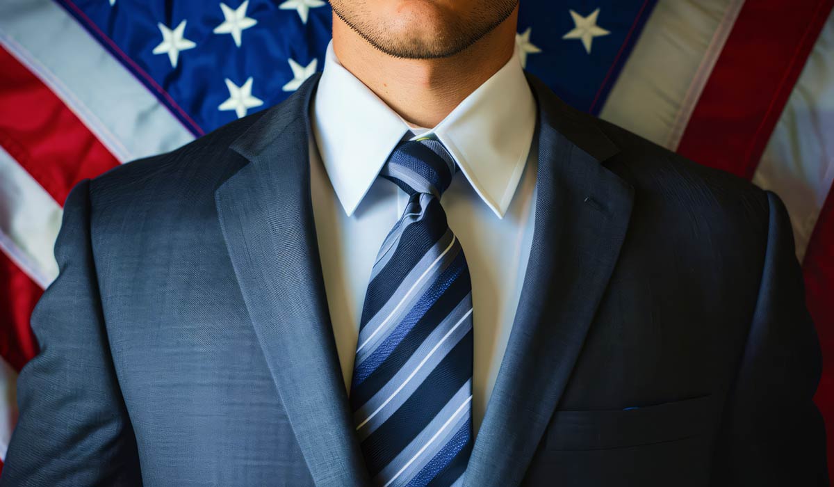 Man Wearing Suit with USA Flag Behind Him Man Wearing Suit with USA Flag Behind Him